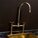 Polished brass bridge faucet installed in traditional kitchen with farmhouse sink – Brass For Homes