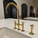 Unlacquered brass bridge faucet with sprayer – installed in farmhouse kitchen